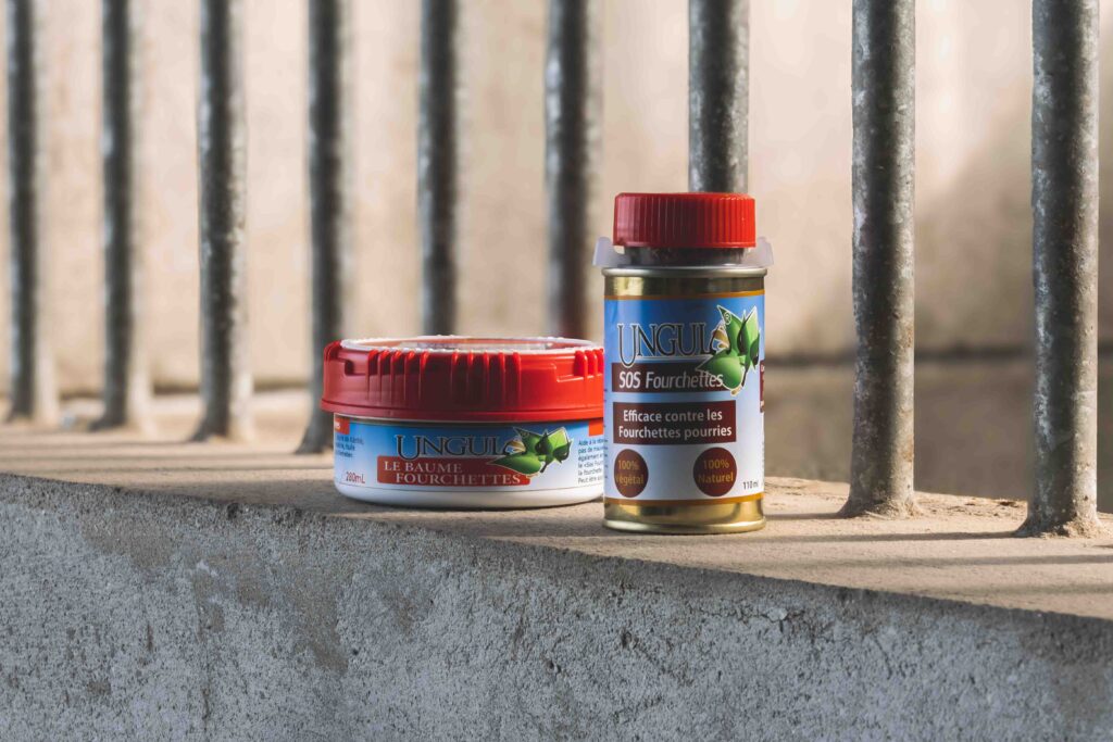 SOS fourchettes et baume fourchettes, deux produits de soins naturels fabriqués par Ungula Naturalis, disposés dans des écuries